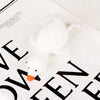 A white, soft duck squeeze toy is shown resting on a piece of paper with black text.