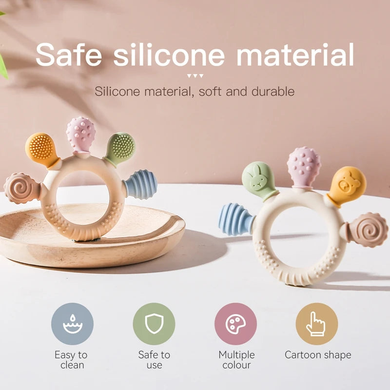 Silikon-Teether-Ring in verschiedenen Farben auf Holzbrett mit Symbolen für einfache Reinigung, Sicherheit und Mehrfarbigkeit