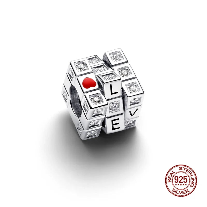 A silver rubik's cube charm with a red heart and letters LVE, set against a white background.