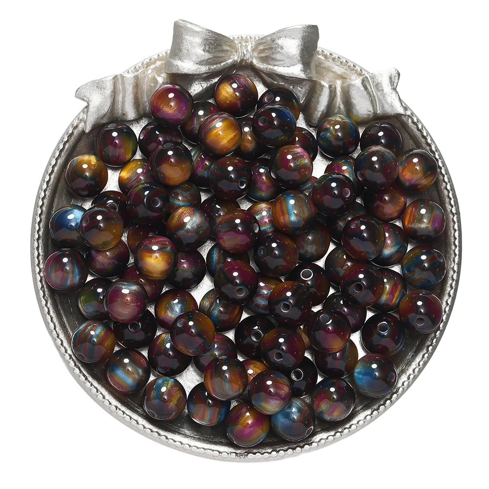 A collection of round, iridescent resin beads in various shades of purple and blue, displayed in a silver-toned dish.