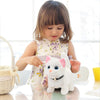 A young girl is interacting with a white plush cat toy that has pink ears and a black collar.