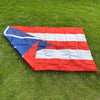 A red, white, and blue Puerto Rico national flag banner laid flat on green grass.