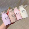 A hand holds several pink and white Chiboki milk bottle stress balls against a light background.