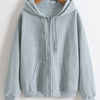 A light gray oversized zip-up hoodie hanging on a wooden hanger.