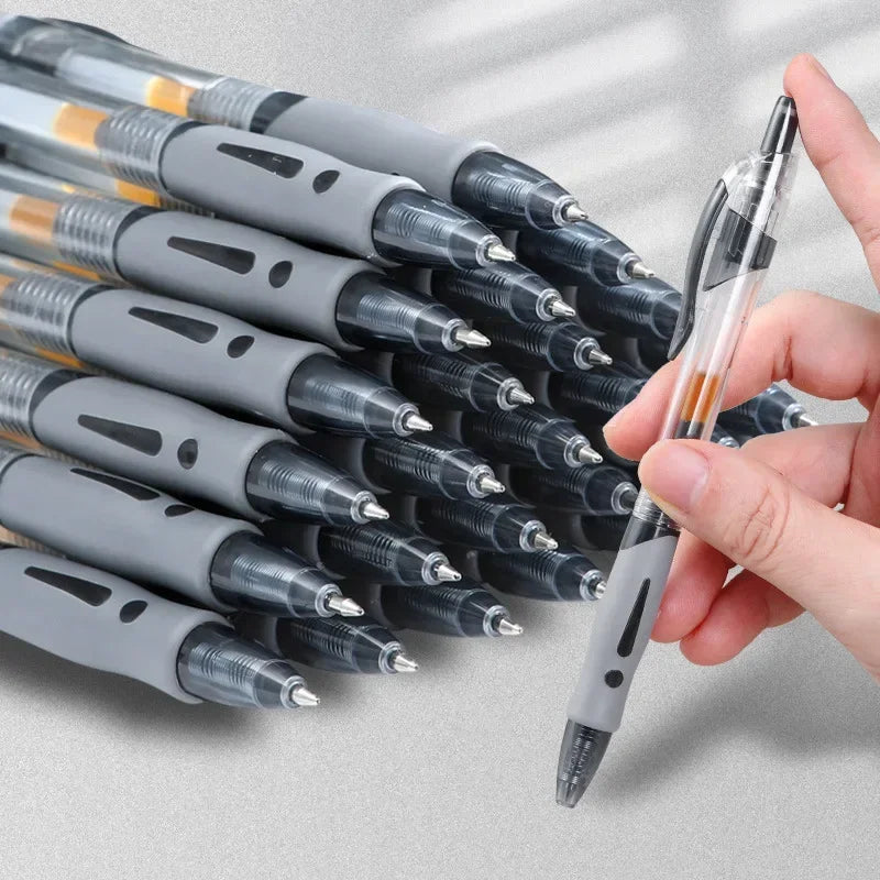 A hand holds a pack of black and silver retractable gel pens with silver tips against a light background.