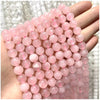 A hand holds a strand of pink rose quartz beads for DIY jewelry making.