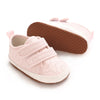 Pink baby first walkers with soft sole and white trim shown from the side.