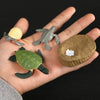 A hand holds a set of three plastic reptiles, including a turtle and a lizard, for an animal life cycle learning kit.