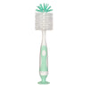A white baby bottle cleaning brush with a teal bristles and a light green handle and suction stand.