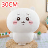 A white Chiikawa plush doll resembling a sleeping character sitting on a woven mat.