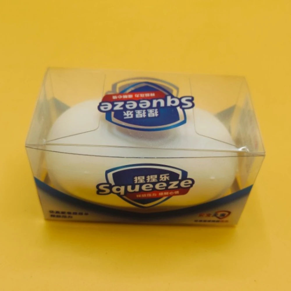 A white squishy stress ball product in its clear plastic packaging on a yellow surface.