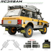 A yellow RC Range Rover model with accessories like mud flaps, fuel tank, and exhaust mufflers.