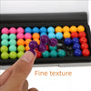 A hand is shown placing colorful beads into a black tray for a logic puzzle.