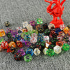 A set of seven polyhedral dice in various colors and shapes, including a large red dragon figurine.