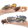 A hand holds a set of realistic mini ocean animal figurines including a whale, shark, dolphin, turtle, and penguin.