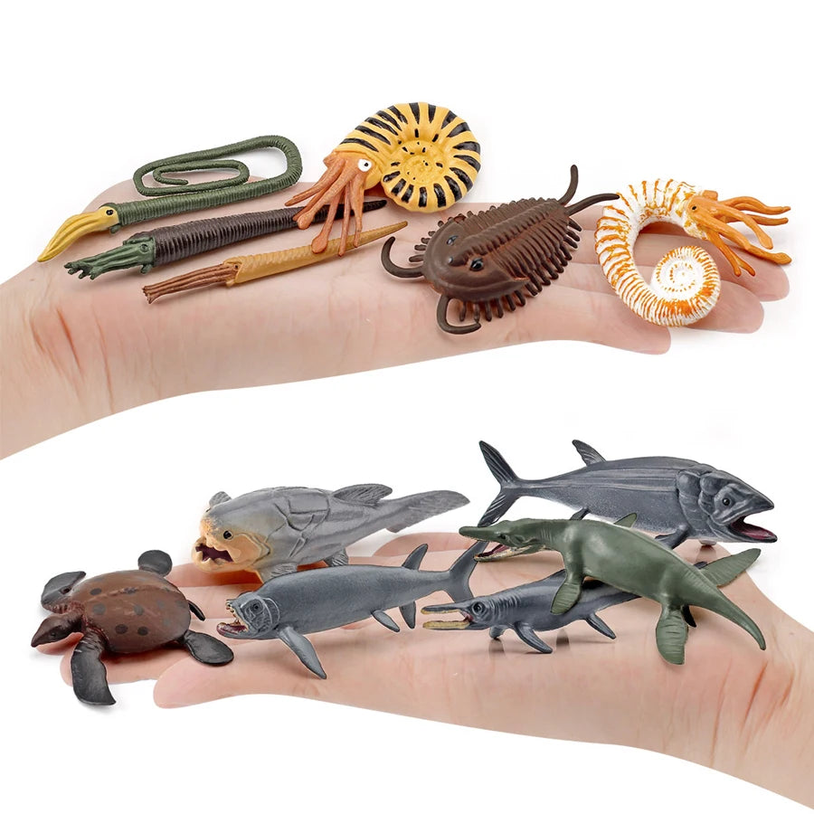 A hand holds a set of realistic mini ocean animal figurines including a whale, shark, dolphin, turtle, and penguin.