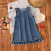A navy blue denim sleeveless dress for a toddler girl with lace trim, resting on a wooden surface.