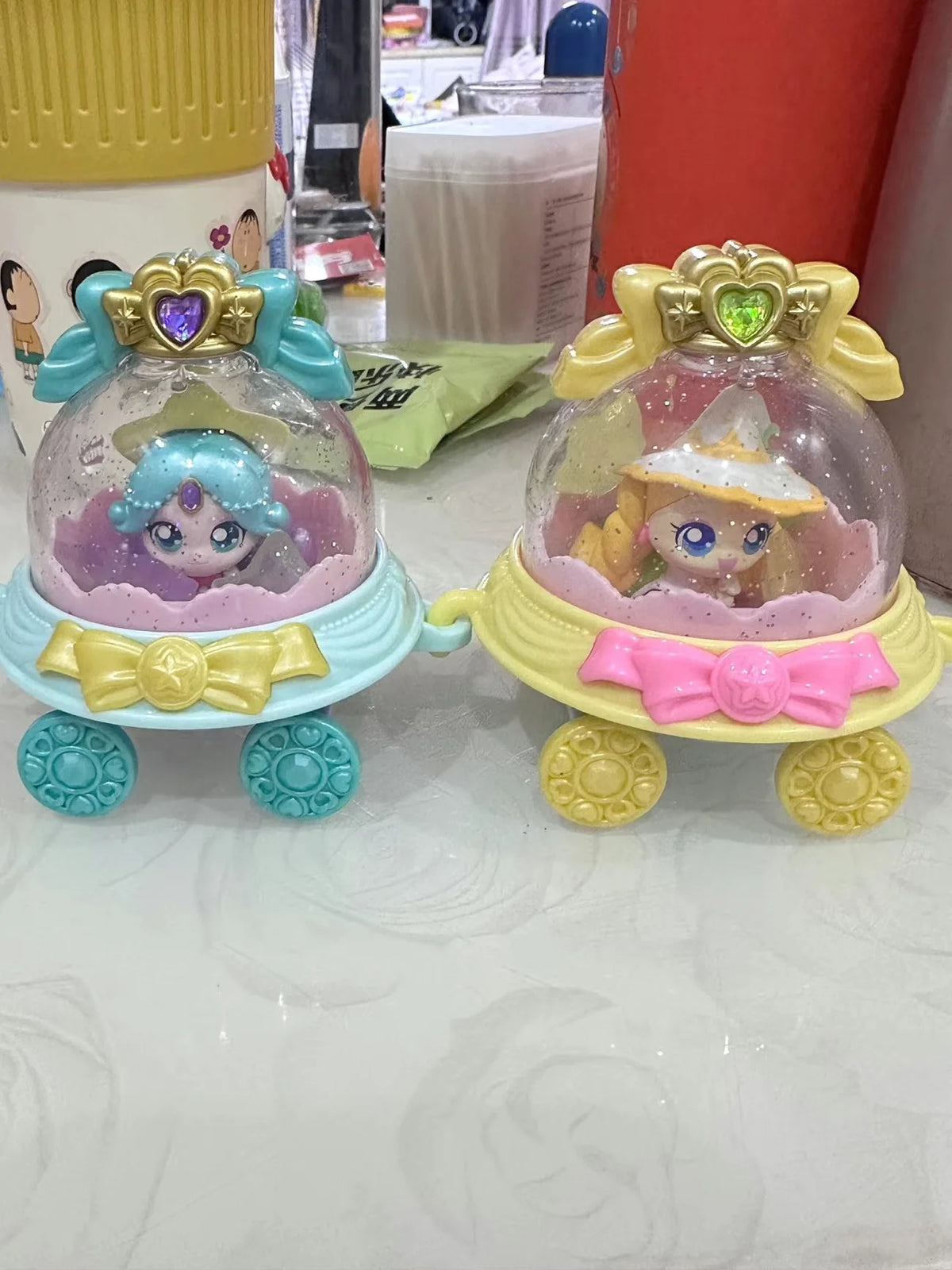 A collectible figure of a doll housed in a clear dome with purple and pink accents, featuring a golden base.