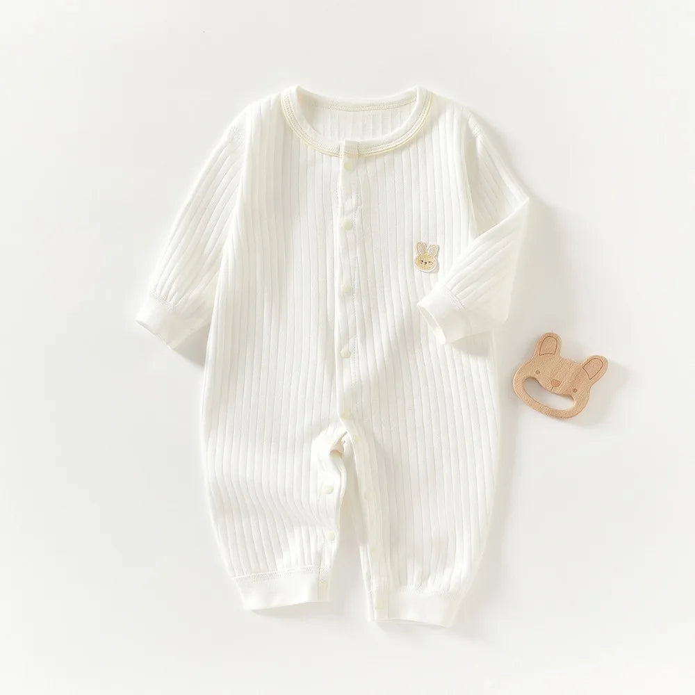A white, ribbed soft cotton baby romper for newborns and infants with a small embroidered detail.