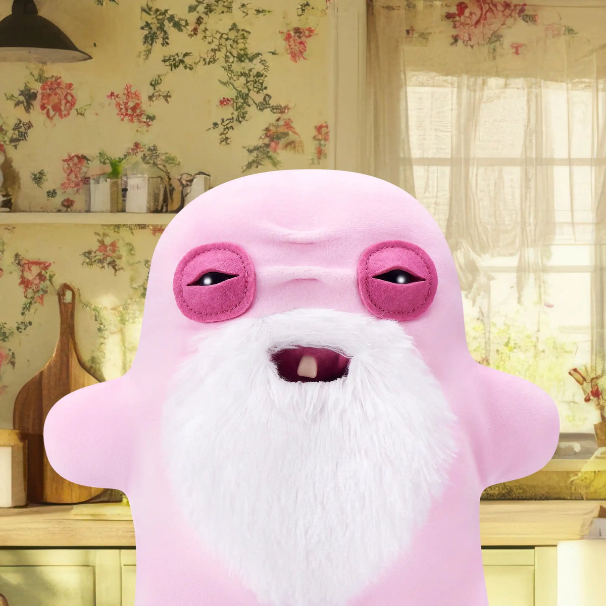 A pink plush monster toy with a white beard and large purple eyes sitting on a wooden surface.