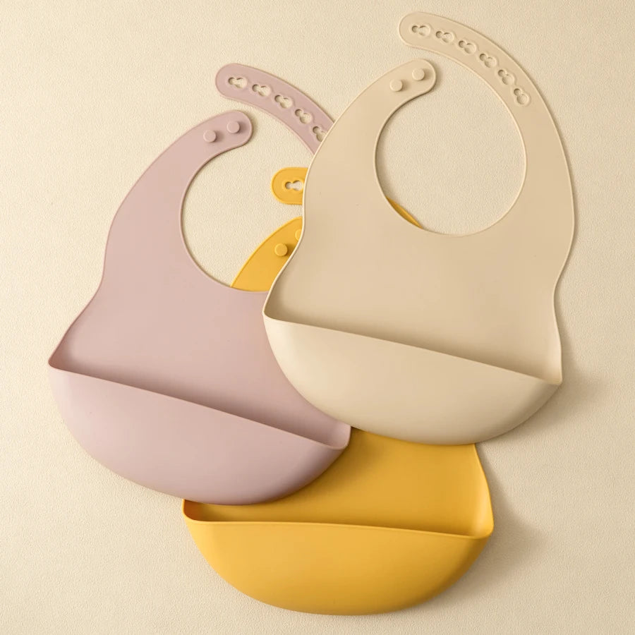 A set of two light pink and cream waterproof silicone baby bibs with adjustable necks displayed against a neutral background.