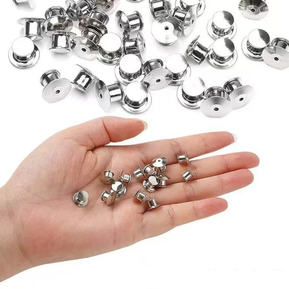 A hand holds numerous metal locking pin backs for brooches, lapel pins, and badges.
