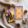 A tarot card featuring The Fool, depicting a figure standing in a landscape with golden light and celestial elements.