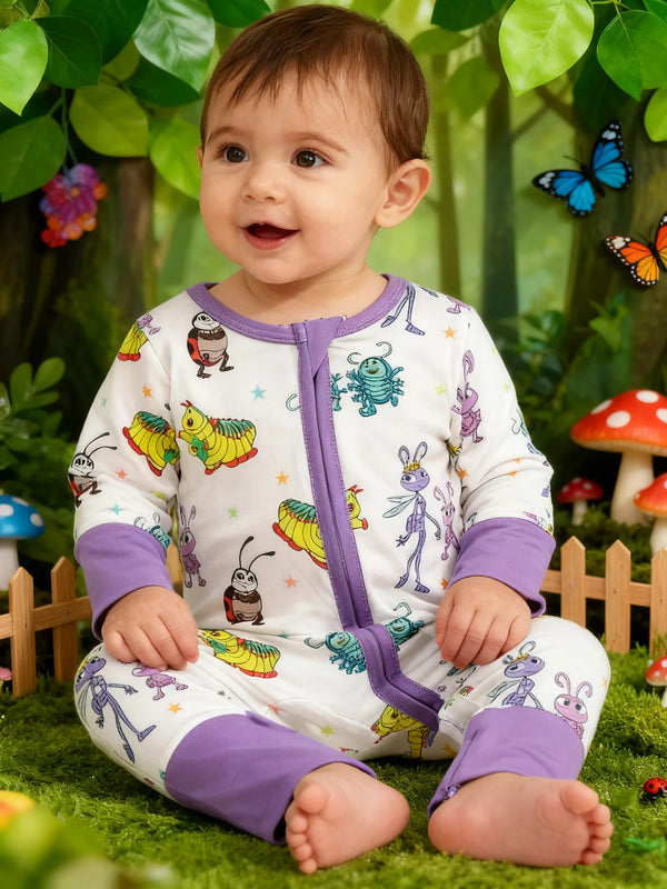 Bébé souriant portant une combinaison en bambou ultra-doux blanc et violet dans un décor extérieur verdoyant.