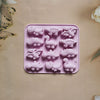 A pink silicone mold with various dinosaur shapes for baking, chocolate, and craft projects.