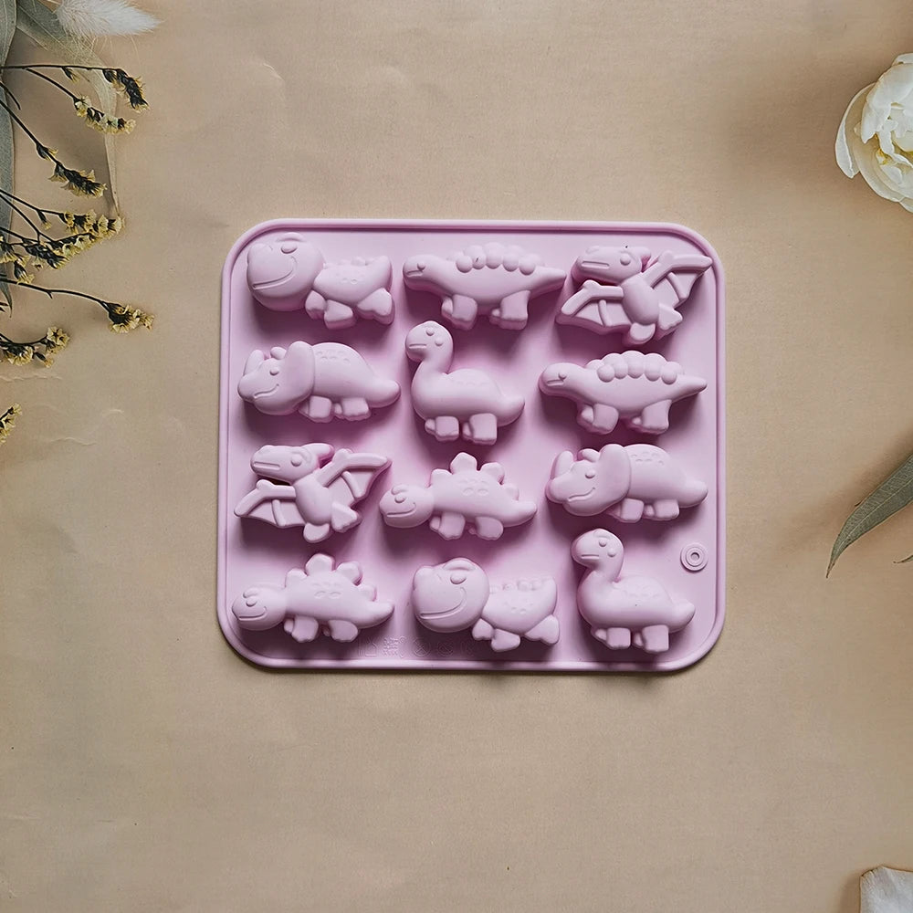 A pink silicone mold with various dinosaur shapes for baking, chocolate, and craft projects.