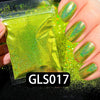 A hand holds a clear plastic container of bright green holographic rainbow nail glitter dust.