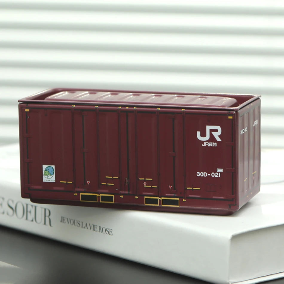 A maroon industrial iron storage box with a lid is shown resting on a white book.