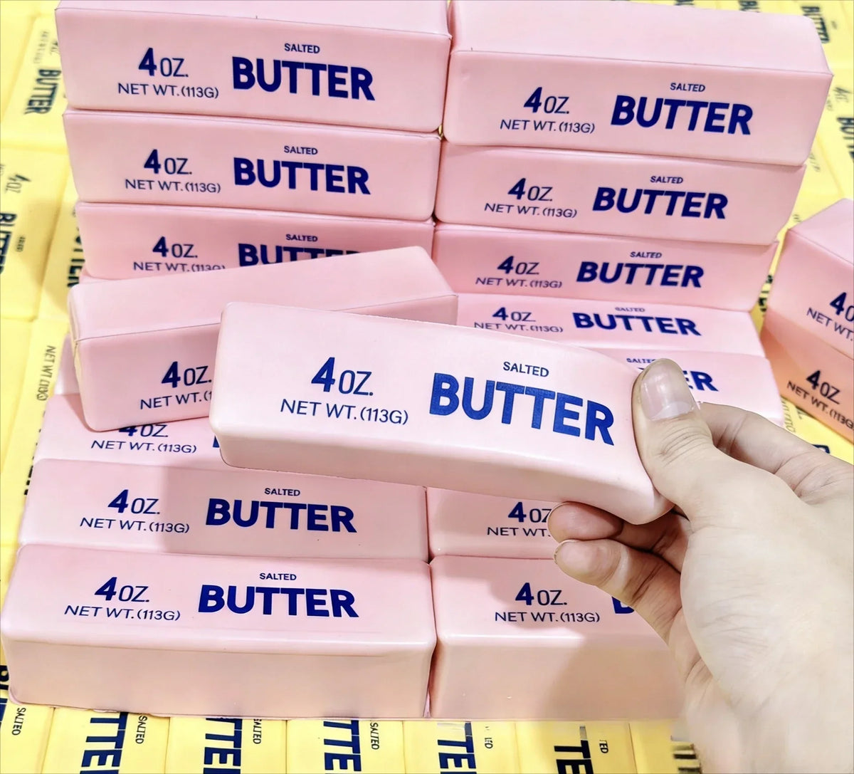 A collection of pink butter squishy stress relief fidget toys packaged in clear plastic.