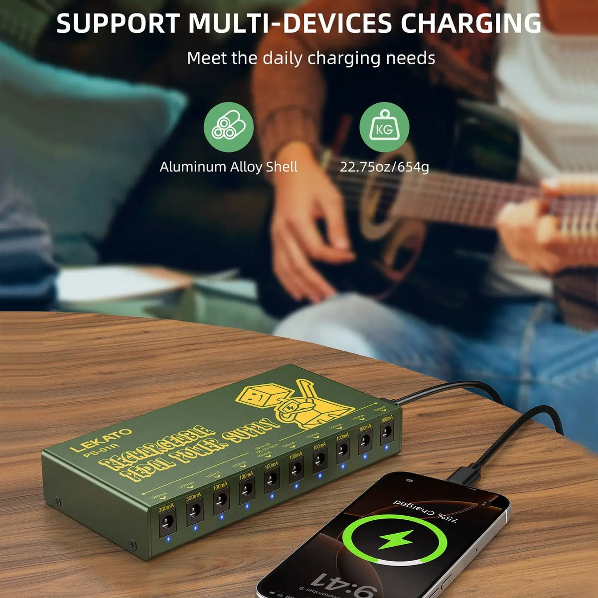 A green portable rechargeable guitar pedal power supply with multiple DC outputs resting on a wooden surface.