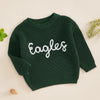 A dark green knit sweater for a baby or kid with white embroidered text spelling out Eagles