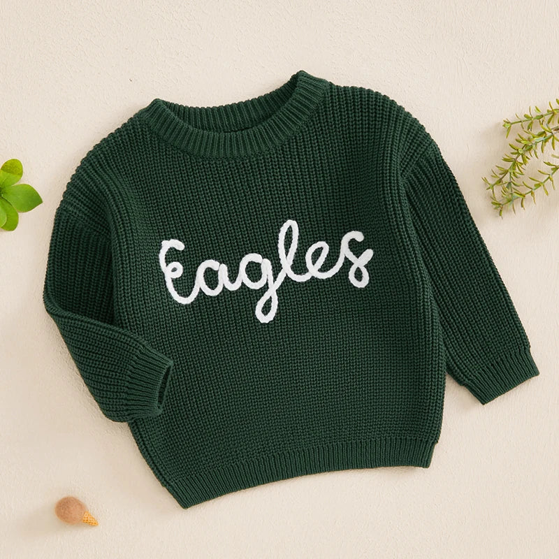 A dark green knit sweater for a baby or kid with white embroidered text spelling out Eagles