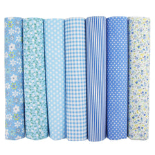 A pack of seven rolled cotton fabric squares in various blue and white gingham, stripe, and floral patterns for quilting.