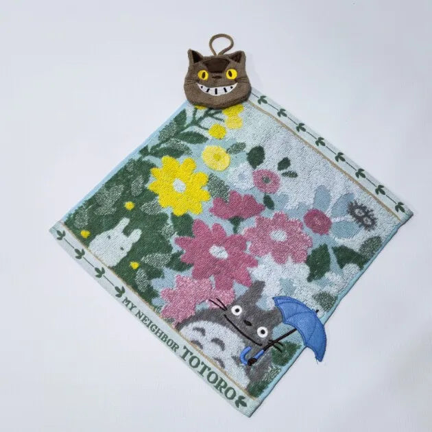A soft stuffed animal plush toy shaped like a hippo, featuring a face and surrounded by floral patterns on a green fabric.