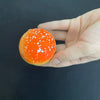 An orange squishy stress ball shaped like a hamburger with white dots