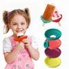 A smiling girl holds an orange drip-proof silicone popsicle holder for kids with various colored silicone popsicles.