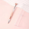 A long, slender pen with a gradient body and a rose gold rotating wax tip is shown next to a clear plastic container.