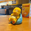 A yellow Milk Dragon decorative figurine sitting in a blue container on a wooden table.