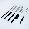 A collection of miniature metal kitchen knives with various blade shapes and handles arranged on a white background.