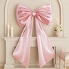 A large pink satin bow decoration displayed on a white mantelpiece.
