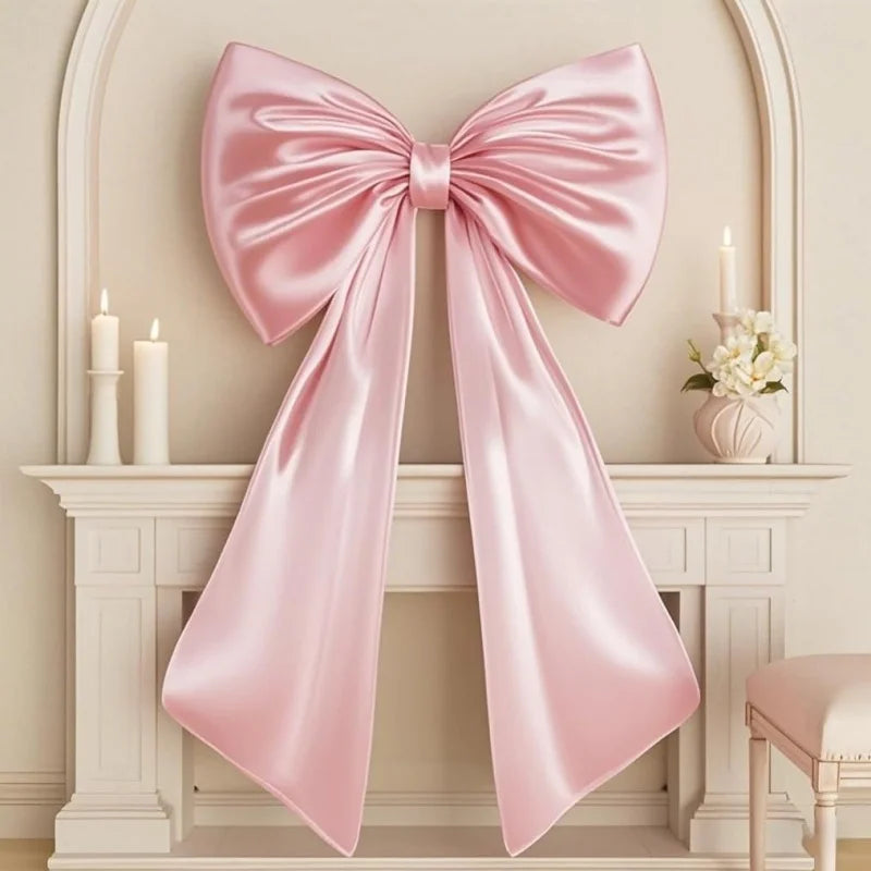 A large pink satin bow decoration displayed on a white mantelpiece.