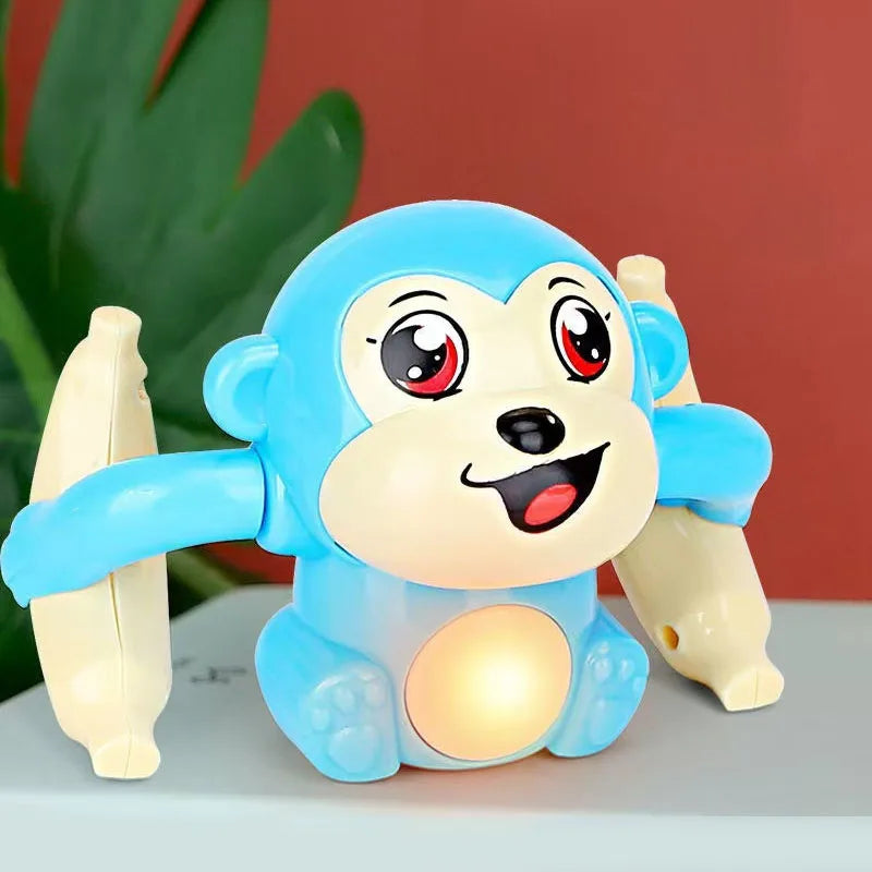 Un jouet singe électrique bleu clair avec de grands yeux et un ventre lumineux, posé sur une surface grise.