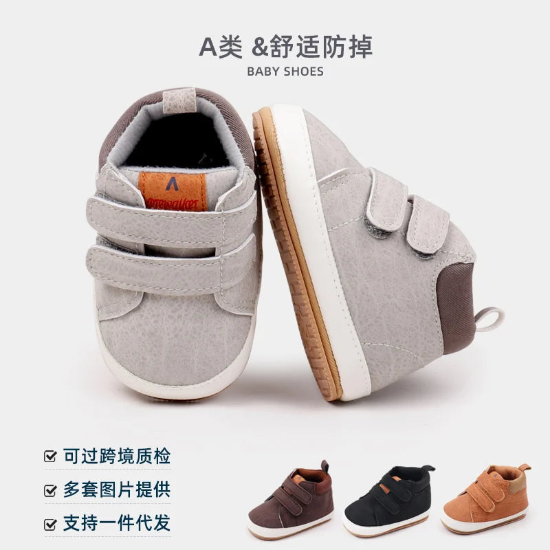 A pair of gray baby shoes designed for first walking, featuring soft PU leather and an anti-slip TPR sole.