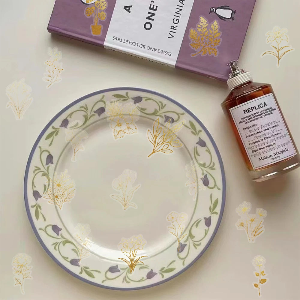 A glass plate with a floral pattern and a bottle of perfume next to a box labeled One Virginia Essays and Lettres