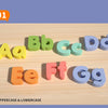 A wooden alphabet puzzle set showing uppercase and lowercase letters in various colors arranged on a light wood surface.