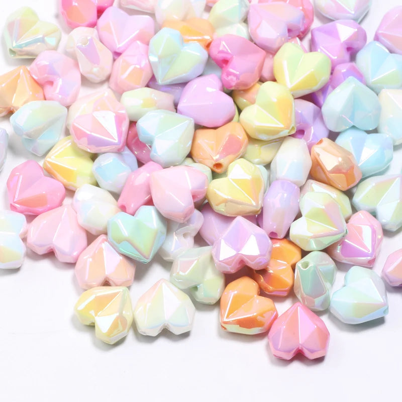 A pile of colorful, iridescent heart-shaped acrylic beads for jewelry making.